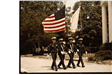 Four uniformed officers march while carrying flags